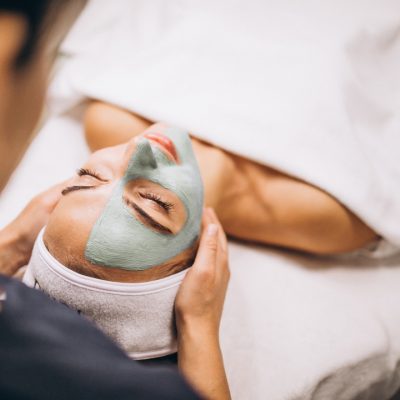 Cosmetologist applying mask on a face of client in a beauty salon